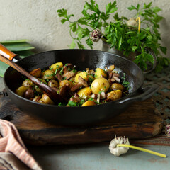 cast iron frying pan with fried new potatoes and boletus mushrooms on the table