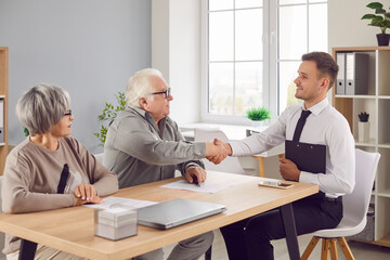 Man realtor assists elderly seniors couple finalizing real estate purchase contract handshake...
