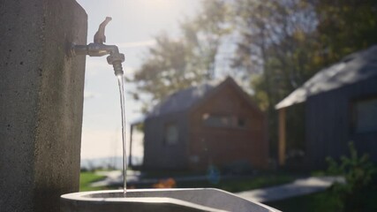Cold refreshing water flowing from the drinking fountain at a camping area in a beautiful rural landscape, close up shot. Nature, and life concepts.