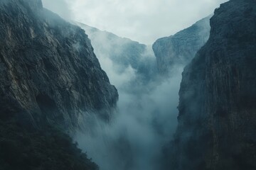 A dramatic view of a deep mountain gorge filled with swirling mist, creating an otherworldly atmosphere
