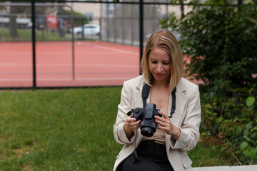 Woman sitting outdoors reviewing camera photos.