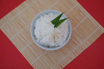 Cooked rice in a bowl with red background, top view.