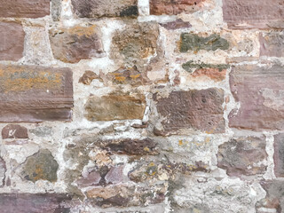 A wall made of stone with a few cracks and some dirt on it. The wall is old and has a rustic appearance