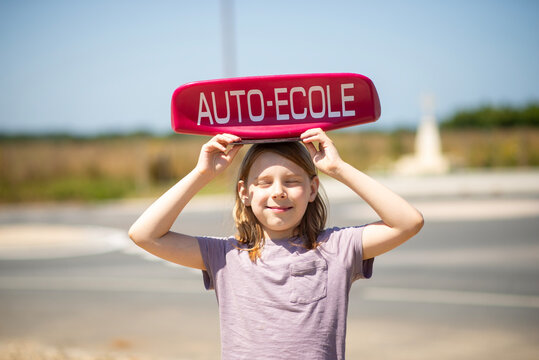 Child Holding Driving School Sign Outdoors on a Sunny Day