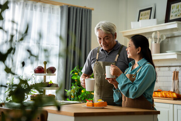 A man and woman are sitting at a table in a kitchen, drinking coffee