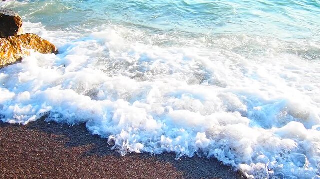 Waves gently lap at shore during stunning sunset over ocean. Golden sunlight reflects off waves as they roll onto shore, creating tranquil atmosphere at sunset by sea. Montenegro summer Canj