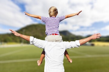 Happy father with small son on field at summer