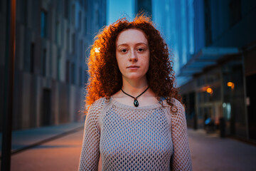 Close-up portrait of a young woman looking at the camera at late night time. Girl wears a serious...