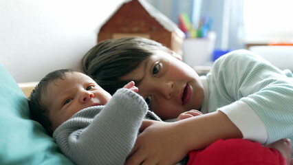 Older sibling interacts lovingly with a newborn baby, capturing a sweet and tender moment of...