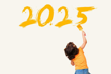 Cute little girl drawing new year 2025 with painting brush on wall background