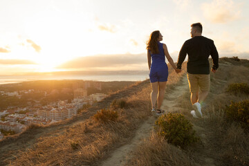 Obraz premium Couple walking away on path at sunset overlooking city