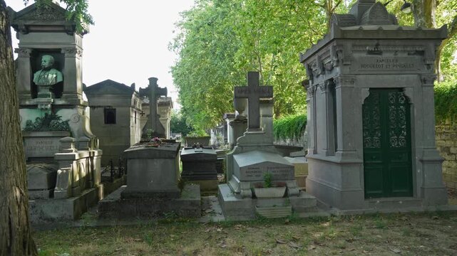 Ancient Parisian cemetery Montparnasse. Tombstones and crypts on graves. Old burial in the shade of trees. Memory of ancestors, peace of mind