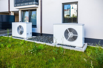 Two air source heat pumps installed outside of new and modern city house, green renewable energy...