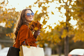 smiling elegant woman in brown trench coat with shopping bags