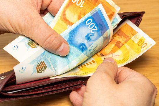 Israel money. Hand taking money out of brown wallet, Israeli shekel banknotes, finance business concept