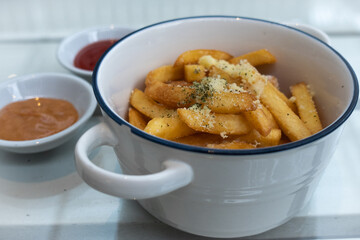 A plate of French fries with a sprinkling of seasoning that looks delicious. French fries are on the table