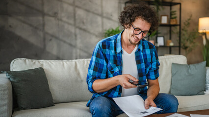 Adult caucasian man do contactless payment on mobile phone at home