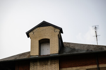 Rustic House Attic with Brick Dormer and Slate Roof in Sunny Weather