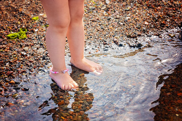 A Childs Joyful Playtime in the Shallow Water on a Pebbly Beach on a Warm Summer Day