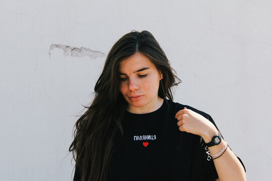A black T-shirt with "????????" and a red heart symbol, worn by a person with long flowing hair. "????????" translates to "Palyanytsia," a term that has become a symbol of Ukrainian identity.