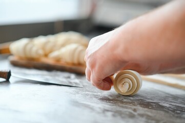 Producing classic croissants at the bakery shop. Woman is rolling dough into rolls for further...