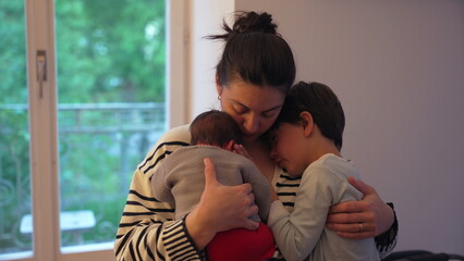 Mother cuddling her newborn and older child, creating an intimate family moment filled with love...