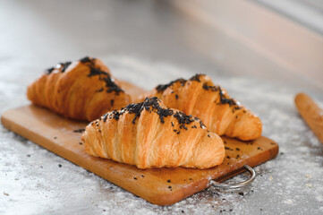 Board with tasty croissants on table, closeup. French pastry