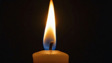 A lit candle emits a warm flame in a dark setting, creating a serene atmosphere