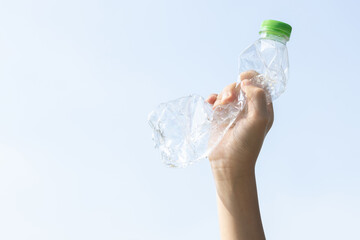 Recyclable plastic bottle held in hand up on sky background. Hand holding plastic waste for recycle...
