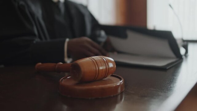 Close up shot of hand of unrecognisable judge hitting sound block with wooden gavel while announcing start of court hearing