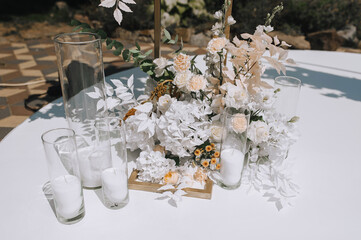 Part, element of decorated wedding arch with flowers, candlesticks standing on white stand outdoors. Close-up photo, decor concept.