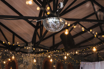 Many lamps, glowing garlands hang on the wooden ceiling in the room, in the interior of a modern...