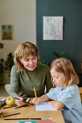 Young mother and her sweet girl coloring painting together during their day off