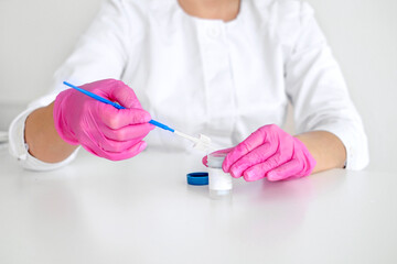 A gynecologist in pink gloves with a brush for taking a swab from the cervical canal for cytological abnormalities