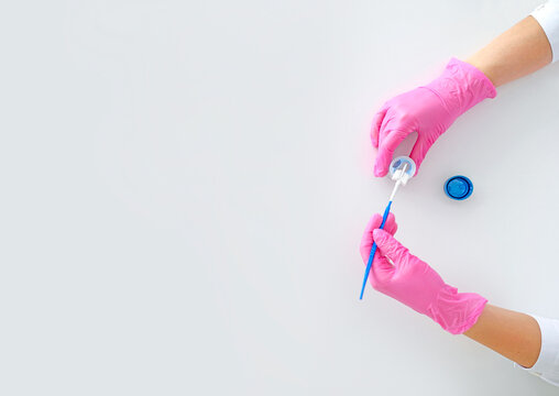 A special brush for taking and microscopic examination of cells from the surface of cervix and cervical canal. Close-up of the doctor's hands in pink gloves in process of work