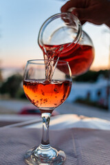 Pouring red wine into a glass at sunset on a serene evening