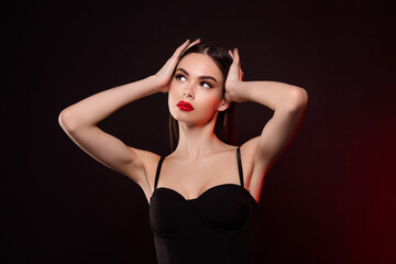 Fototapeta premium Photo of lady in black dress touch hair adjust haircut lok empty space isolated dark neon color background