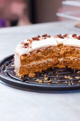Pastel de zanahoria sobre una mesa gris con betún blanco y nueces arriba. 