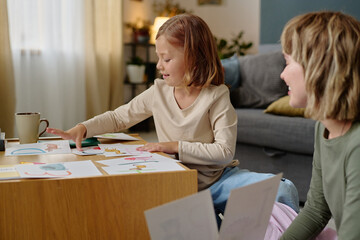 Little Girl sitting at table and learning alphabet while her mom helping her