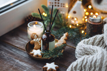 Christmas home aromatherapy. Aroma diffuser with pine extract, organic essential oil, cedar and spruce cone, cinnamon, anise, vanilla scent, candles, wooden table. Cozy atmosphere, winter inspiration