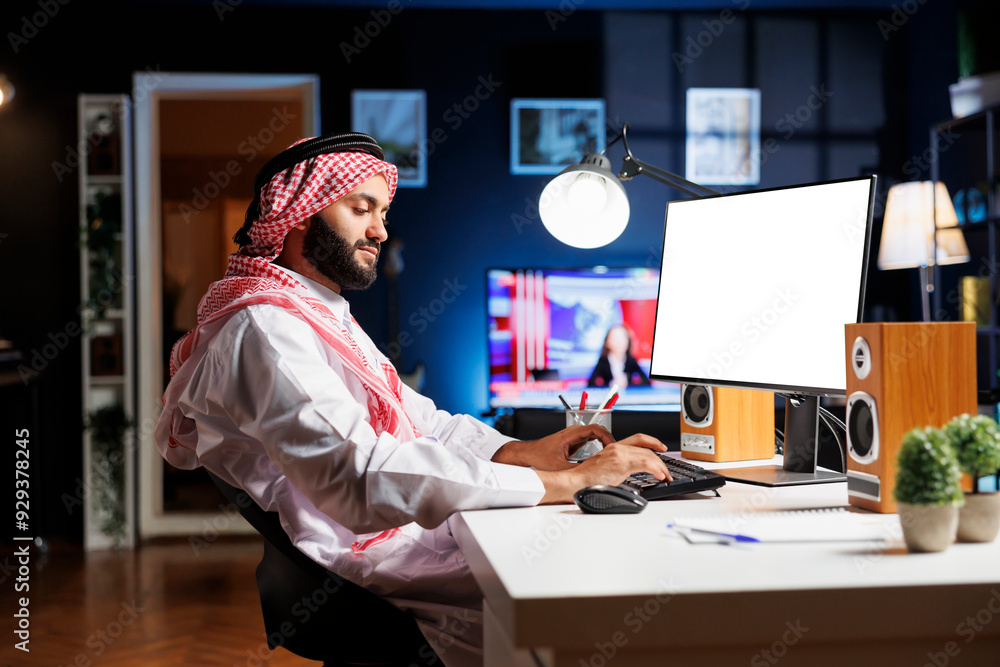 Aufkleber side-view of arab man sitting at the table with his pc monitor displaying an isolated chromakey temp