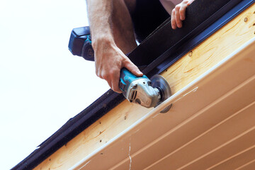 Cutting down existing vinyl soffit plastic panels to a given size on facade ceiling of new home