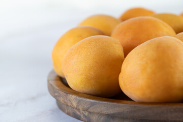 Ripe apricots on a wooden plate, close-up. Fresh natural apricots, delicious summer dessert, emphasis on detail, close-up, high resolution.
