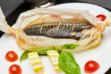 Gourmet baked mackerel in parchment with lemon slices, basil, and cherry tomatoes
