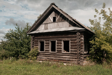 An old log cabin is situated in the middle of a grassy field