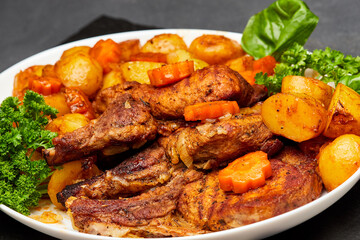 Roasted lamb with golden potatoes and carrots, garnished with fresh herbs for a hearty meal