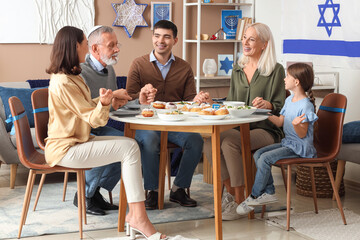 Happy Jewish family having dinner at home on Hanukkah