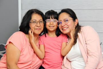 Three Generations of women Grandmother, mom and brunette Latina daughter with glasses show their...