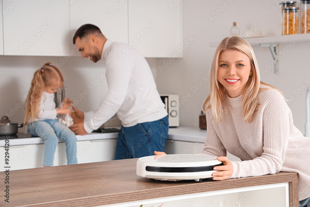 Poster Happy mother with robot vacuum cleaner and her family in kitchen