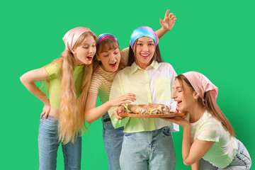 Happy young women with doner kebabs on green background
